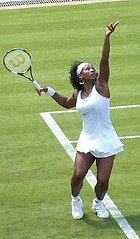 Image of a woman serving a tennis ball.